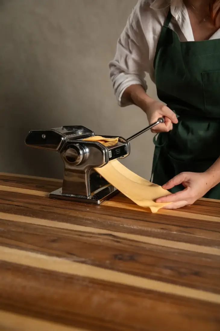 Chef Sofia Marinho passando a massa em um rolo para produzir massas artesanais
