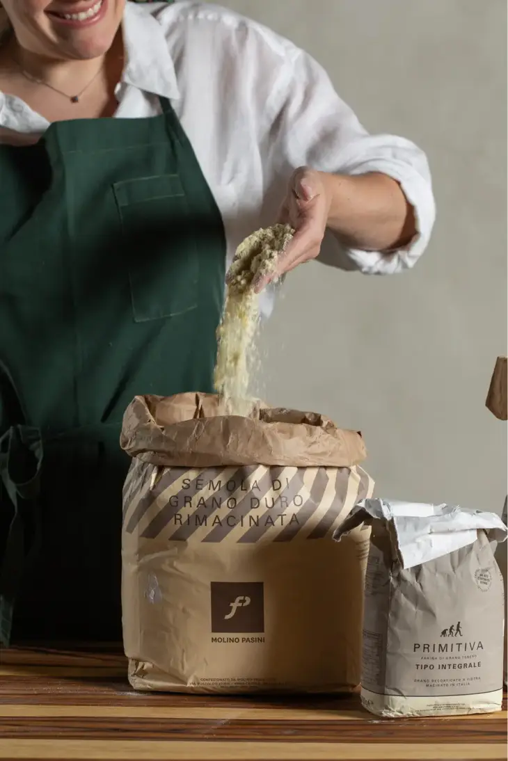Chef Sofia Marinho pegando semola grano duro de um saco, para preparar massas artesanais